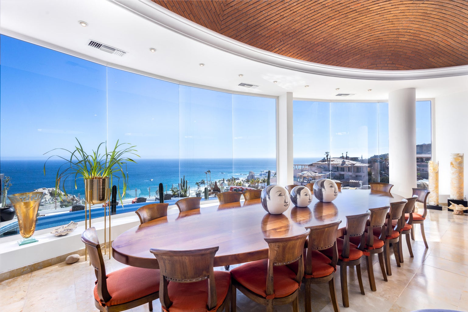 Curved panoramic dining room with floor-to-ceiling glass walls, 180-degree ocean views, parota wood table