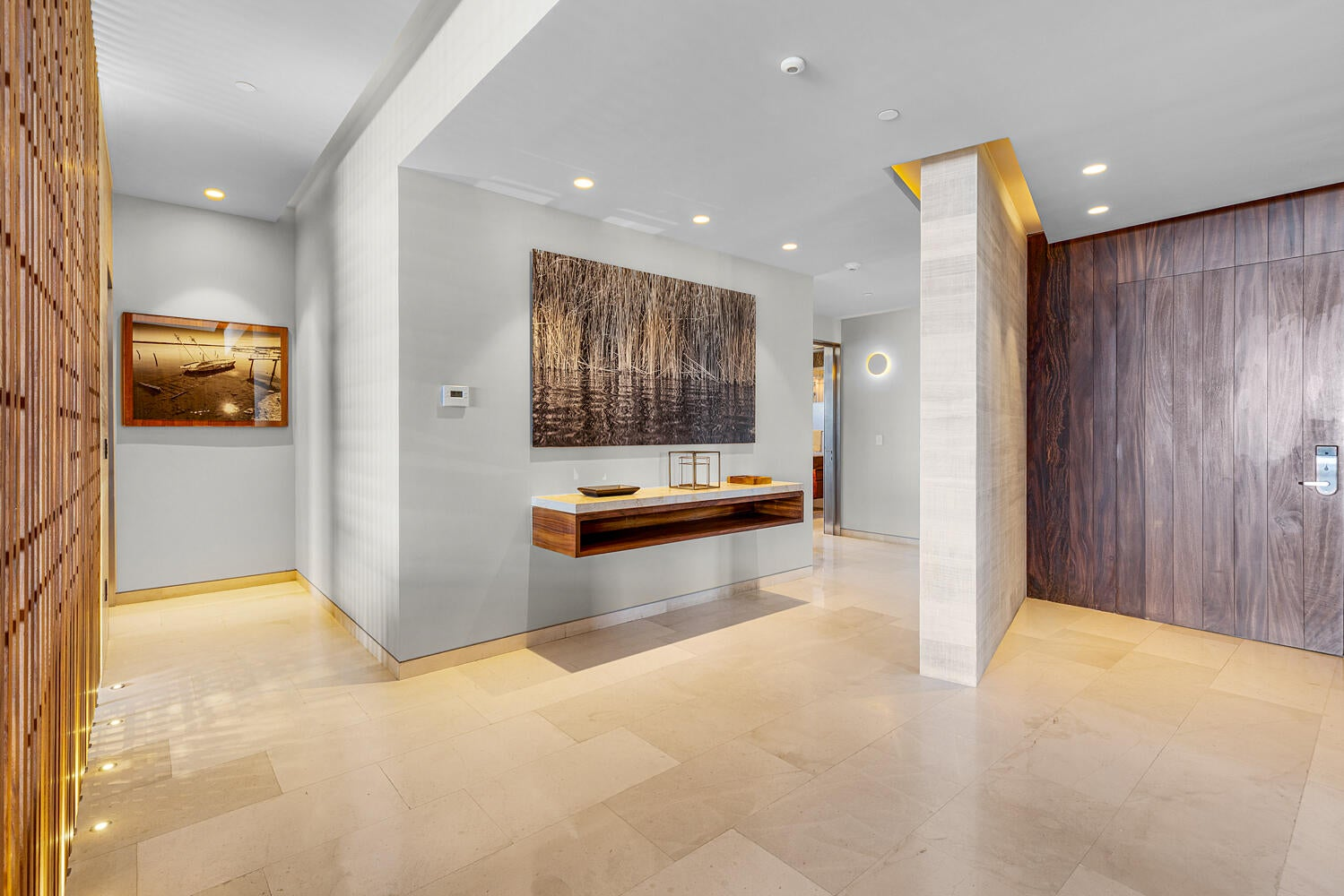 Gallery-style entry foyer with contemporary art, marble floors, and rich wood paneling