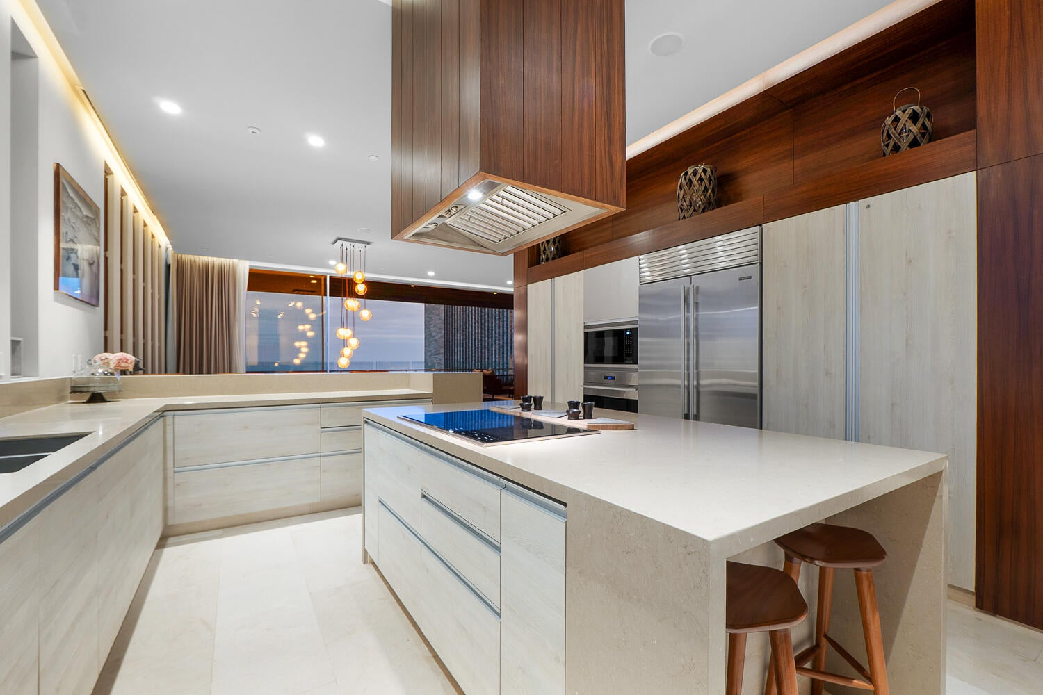 Chef's kitchen with large island, rich dark wood cabinetry, professional-grade appliances, warm ambient lighting